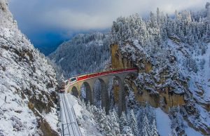Το κόκκινο τρένο των Χριστουγέννων: Η μαγευτική διαδρομή μέσα από 55 τούνελ και 196 γέφυρες στα χιονισμένα βουνά