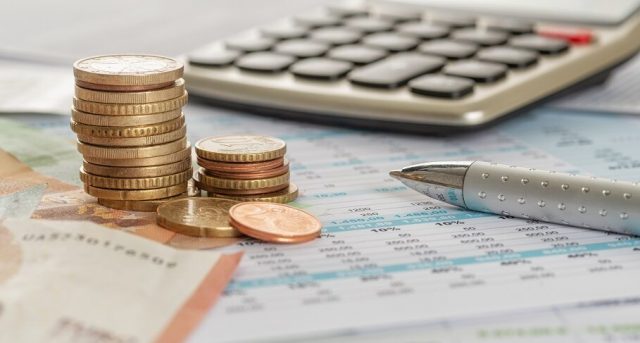 Euro bills and coins on documents with a calculator