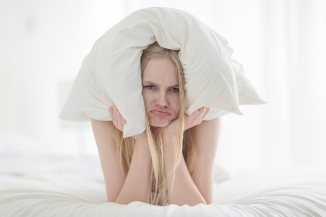 Grumpy,Woman,In,Bed,Covering,Ears,With,Pillow,Because,Of